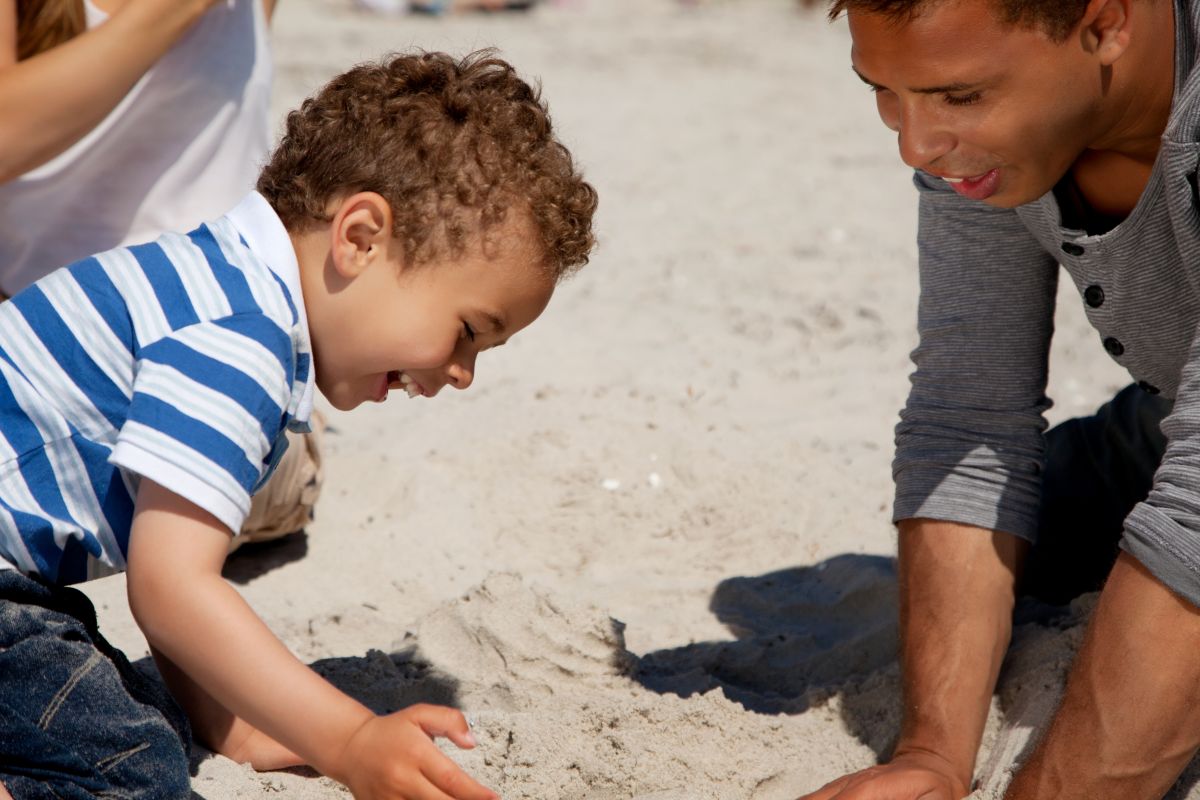 Kind mit Vater spielt im sand